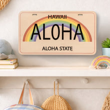 Load image into Gallery viewer, Decorative license plate with rainbow and 'Aloha' text on a shelf with decorative items.
