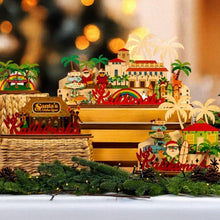 Load image into Gallery viewer, Decorative Christmas scene with Santa&#39;s Village set, palm trees, and tropical elements on a blurred background.
