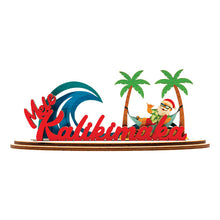 Load image into Gallery viewer, Decorative 3D holiday sign with &#39;Mele Kalikimaka&#39; script, Santa Claus in a hammock, a blue wave and palm trees on a white background

