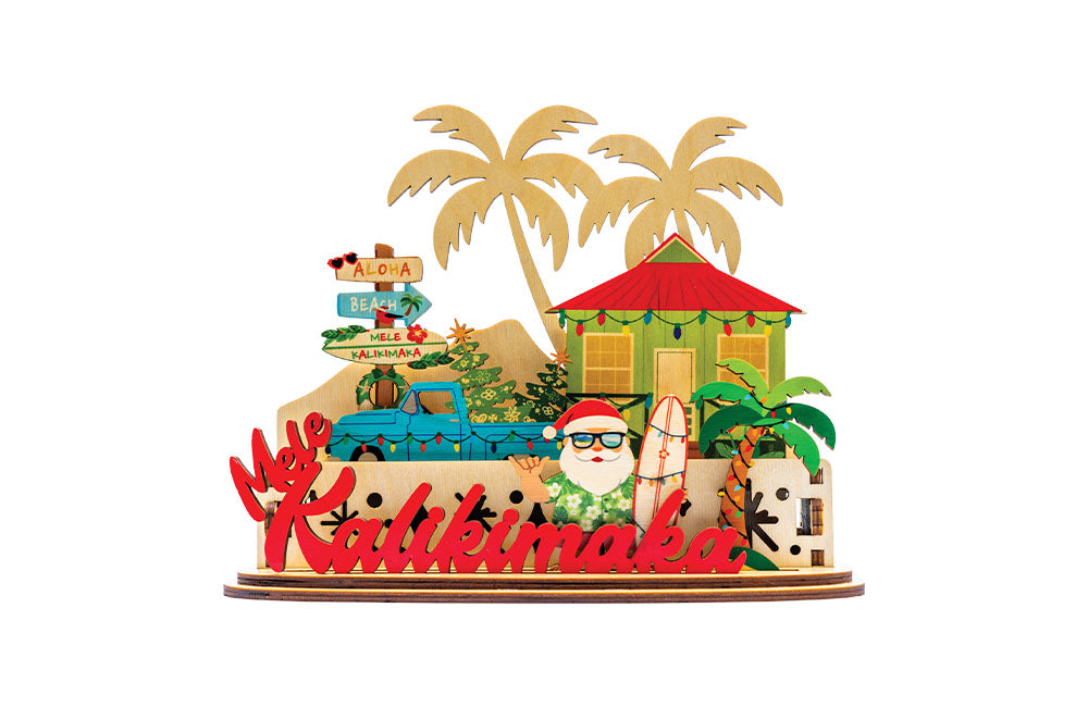 Decorative 3D holiday tiered sign with Santa holding a surfboard, a blue truck, beach shack and other tropical elements with 'Mele Kalikimaka' script on a white background