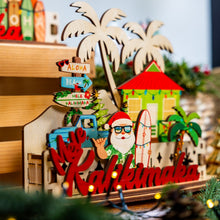 Load image into Gallery viewer, Decorative 3D holiday tiered sign with Santa holding a surfboard, a blue truck, beach shack and other tropical elements with &#39;Mele Kalikimaka&#39; script in a festive Christmas village scene
