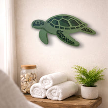 Load image into Gallery viewer, Green turtle layered wall decoration on a neutral wall with towels and a plant below.
